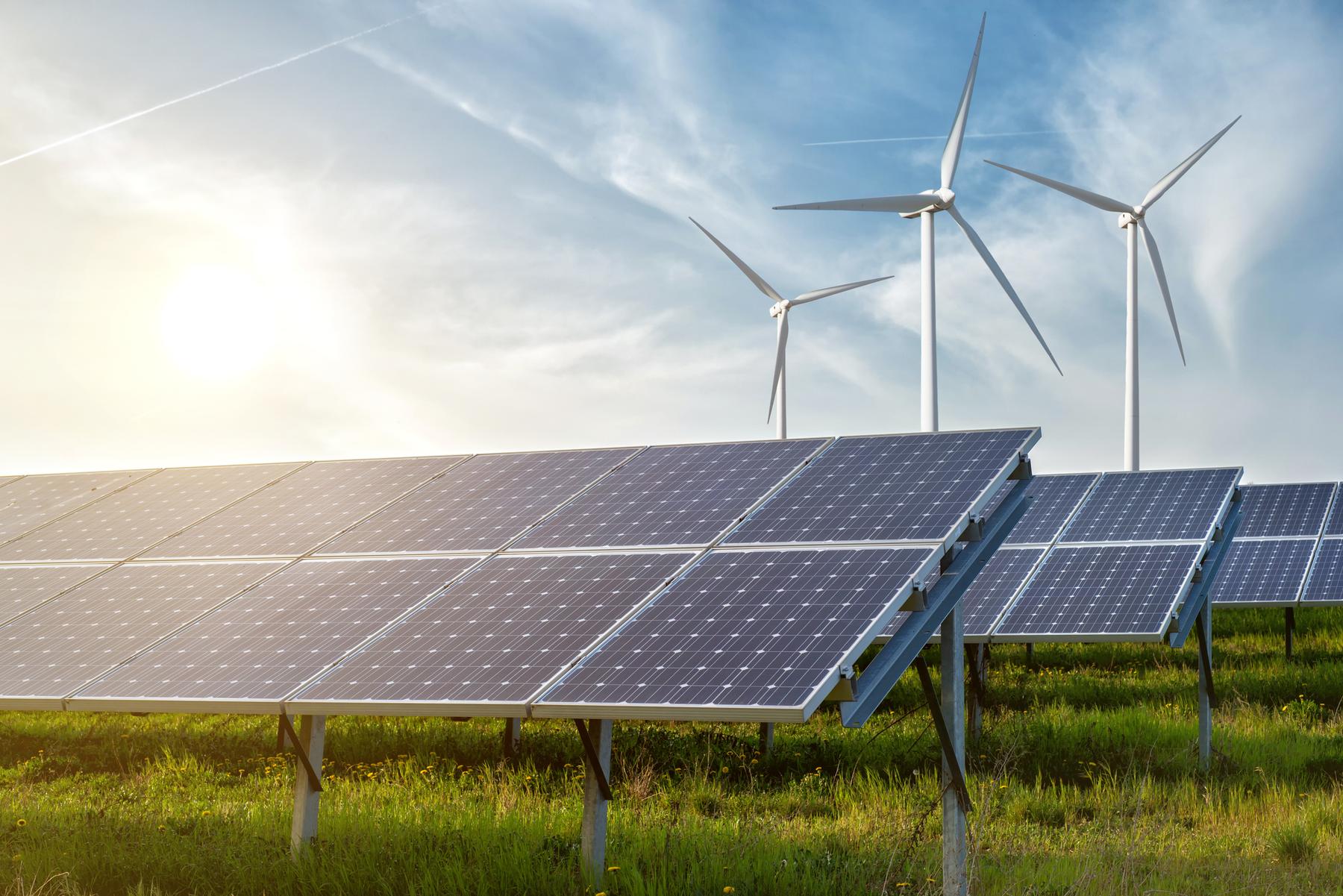 Solar panels and wind turbines sharing farmland, renewables and resources on the same ground.