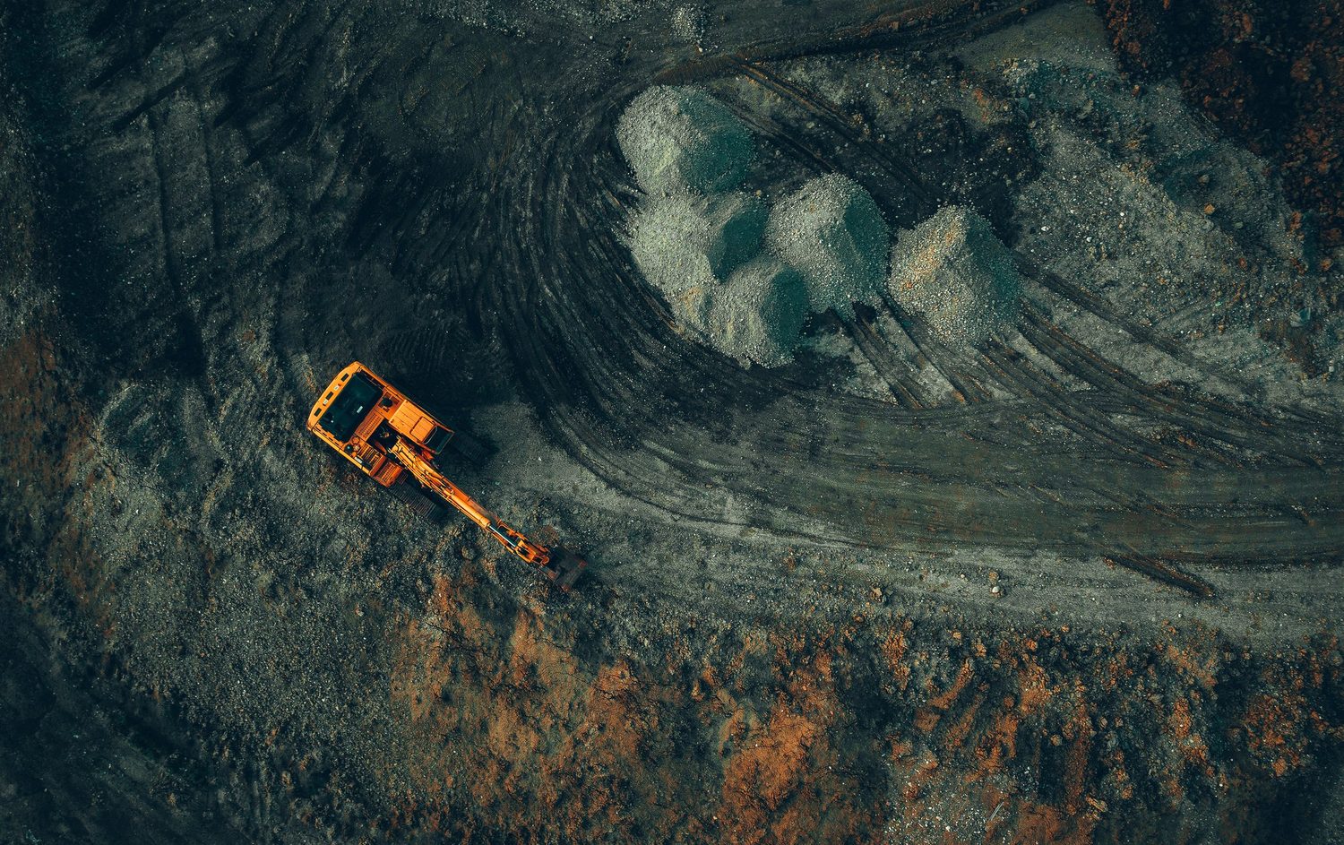 Aerial view of a working excavator at a mine site — environmental and heritage exposure.